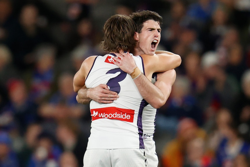 Andrew Brayshaw yells while receiving a hug from Caleb Serong
