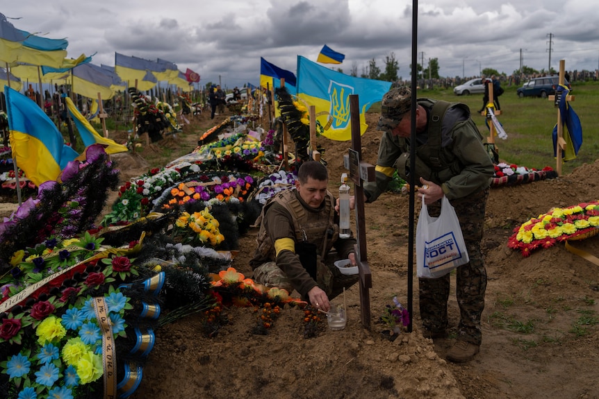 Two national guard visit the grave of a late soldier