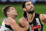 A Geelong AFL player pushes against a Collingwood opponent as they prepare to contest for the ball in Perth.