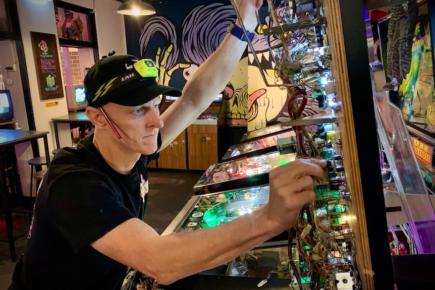 James Angliss, aka Jimmy Nails, works on a pinball machine in his arcade Netherworld in Brisbane.