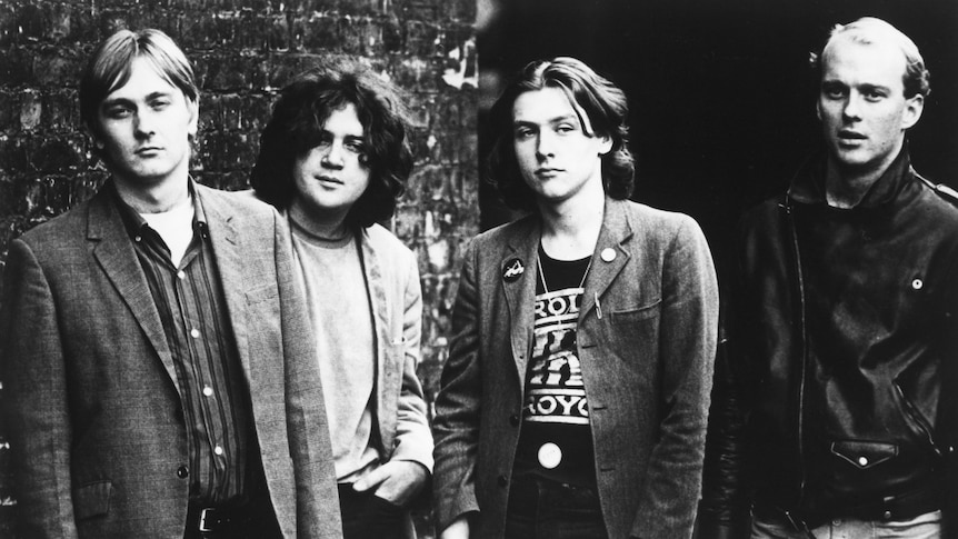 black and white photo of punk band the saints standing before a brick wall