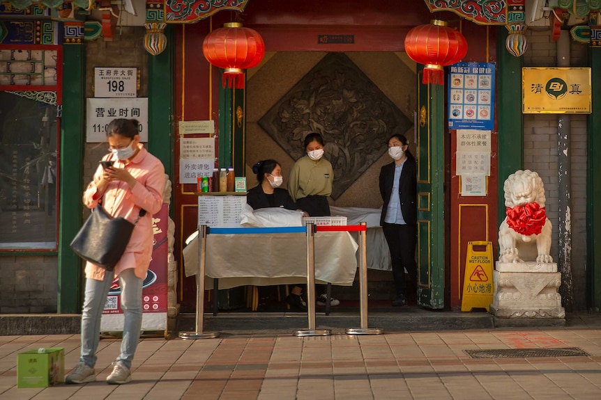 Clerks wear face masks as they wait for customers at a Beijing restaurant.