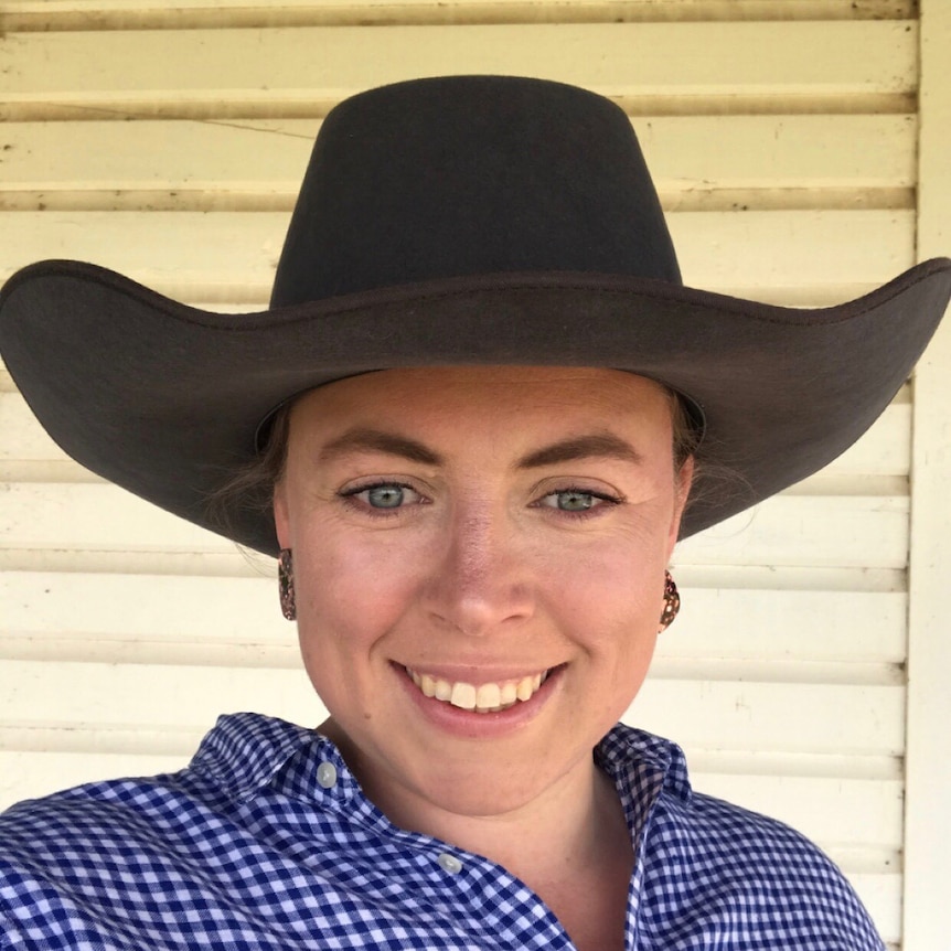 A woman with a bush hat looks a the camera and smiles in a selfie.