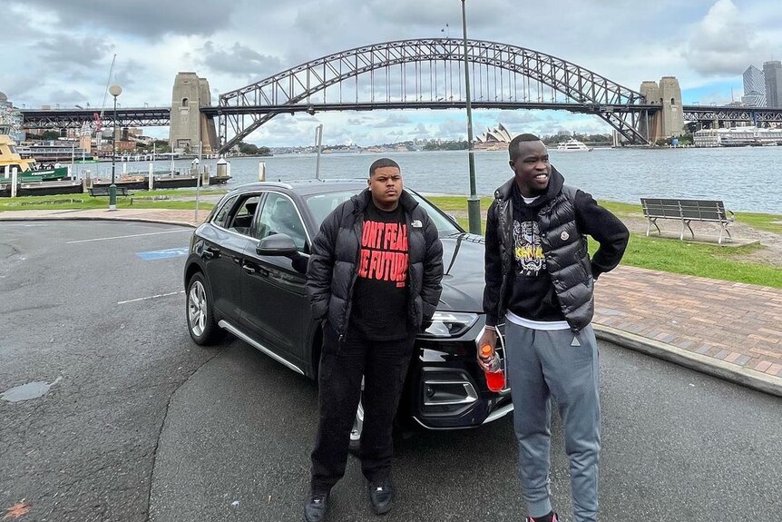 Two young men standing behind the Sydney Harbour Bridge.