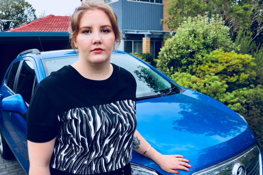 Young woman Amy Nivison-Smith standing in front of a car.