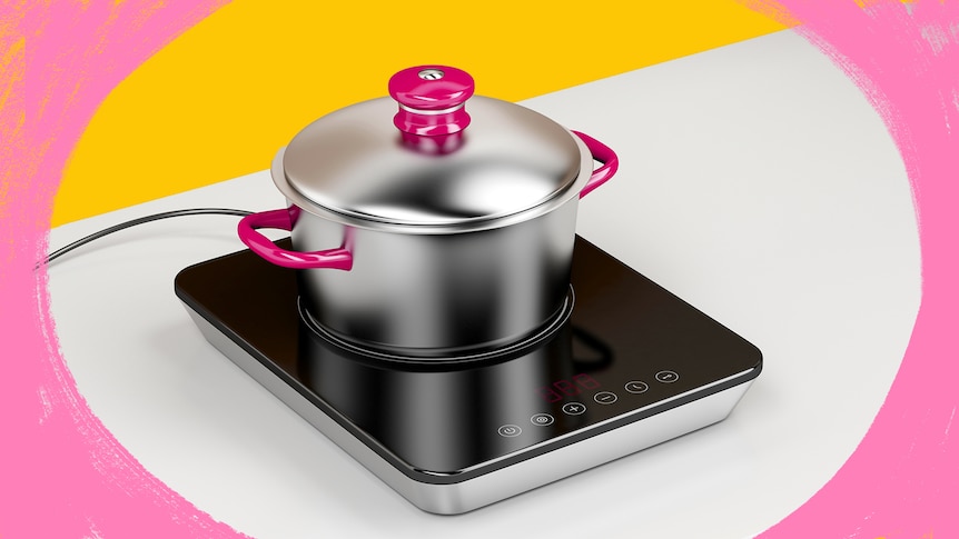 A black portable induction stove is seen sitting on a white countertop under a stainless steel pot with pink handles and knob 