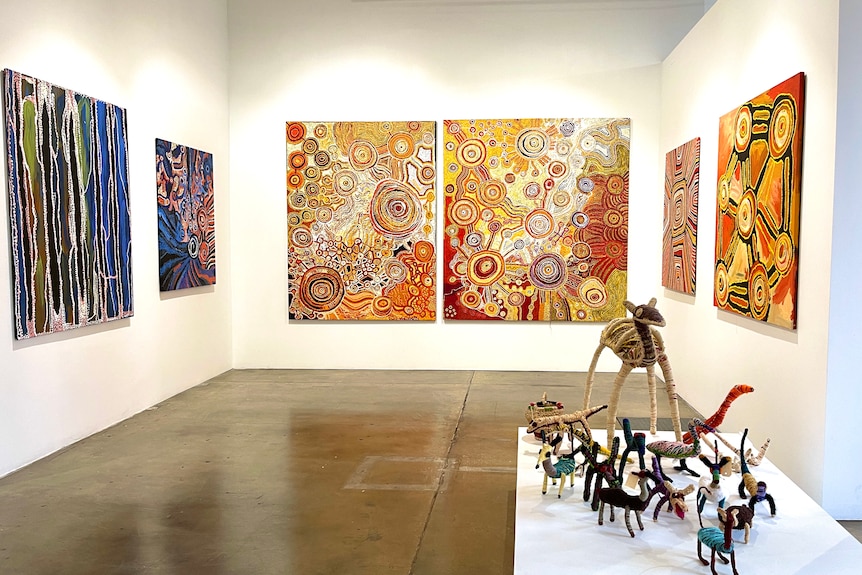 Indigenous art including paintings and sculptures displayed in a gallery.