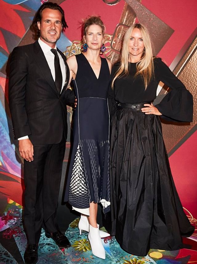 Three people stand on the red carpet.