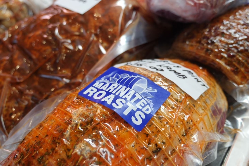 A packaged marinated roast sits in a butchers window