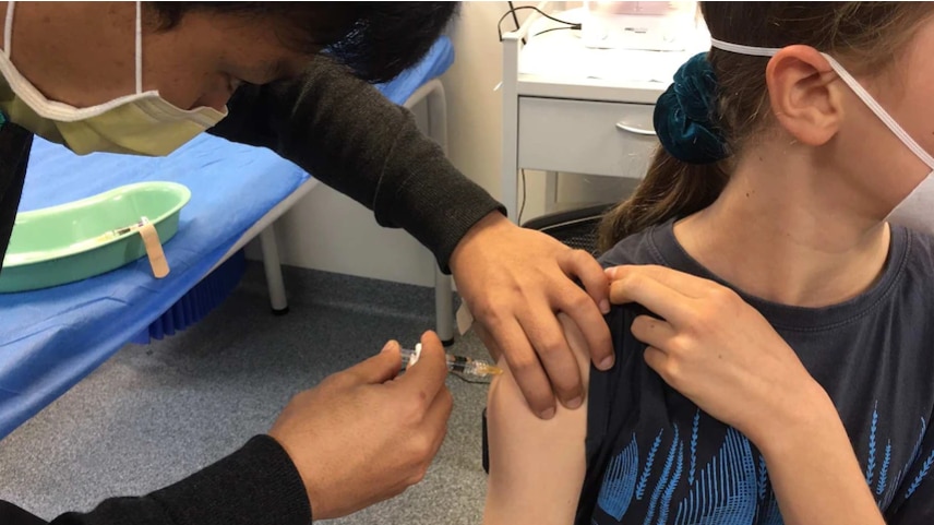 A health practitioner administers a vaccine to a teenage girl.