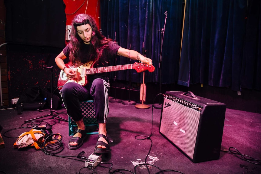 Camp Cope singer Georgie Maq tunes her guitar