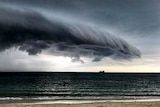 A menacing cloud hovers over the water off a beach.