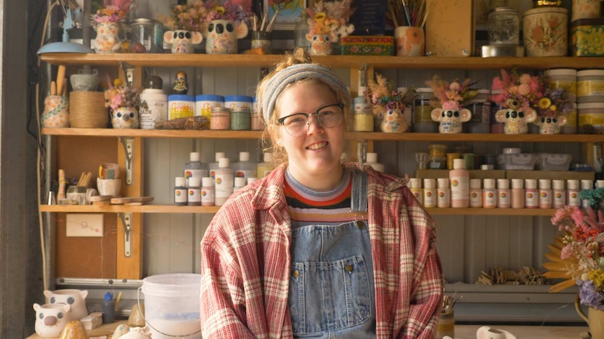 A smiling young woman in a pottery studio.