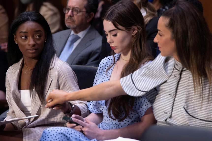 A group of women sitting in the US Congress, from left Simone Biles, McKayla Maroney and Aly Raisman