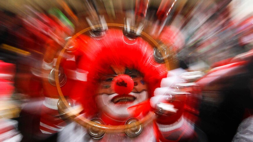 A woman dressed as clown playing a tamborine celebrates "Weiberfastnacht" (Women's Carnival) in Cologne
