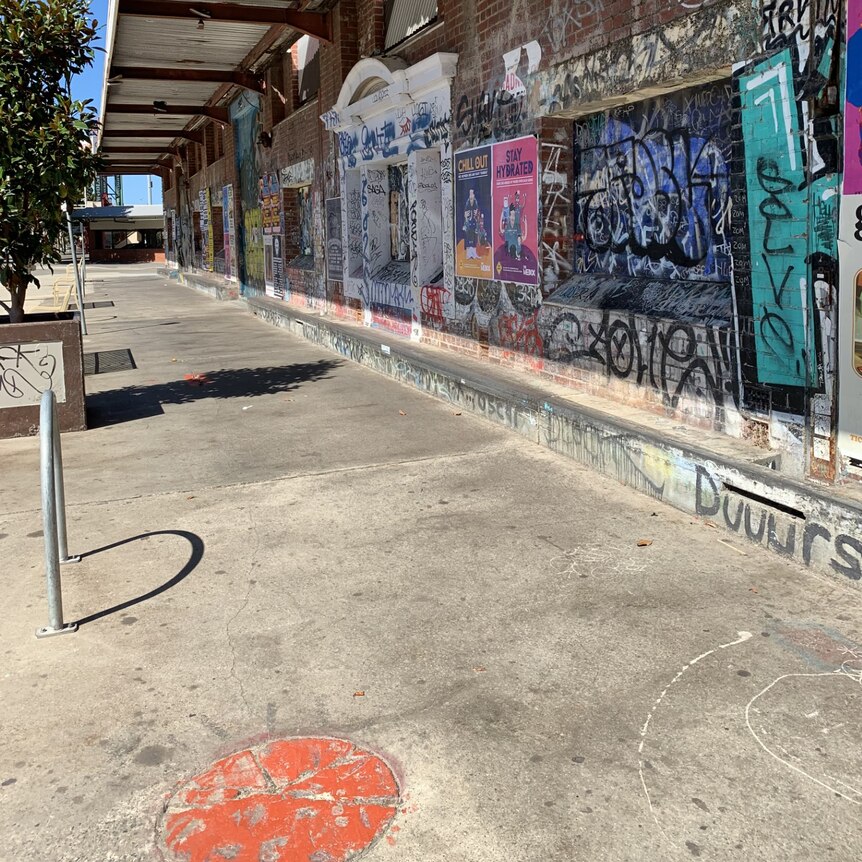 Image of the outside old warehouse covering with colourful graffiti and cement floors and a cement ledge