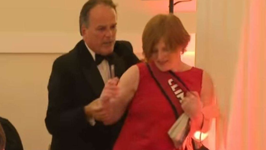 Mark Field grabs a woman in a red dress