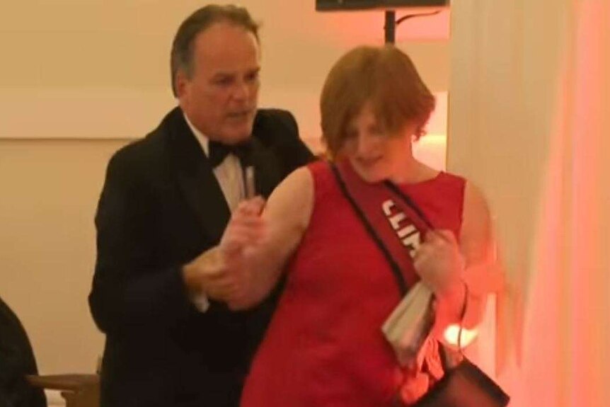 Mark Field grabs a woman in a red dress