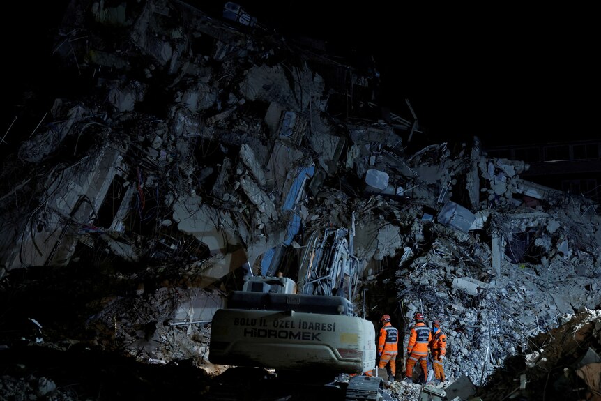 emergency workers in uniform walk into rubble searching for people in Antakya