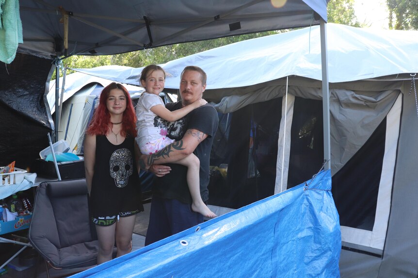 A family standing in front of the tents they live in.