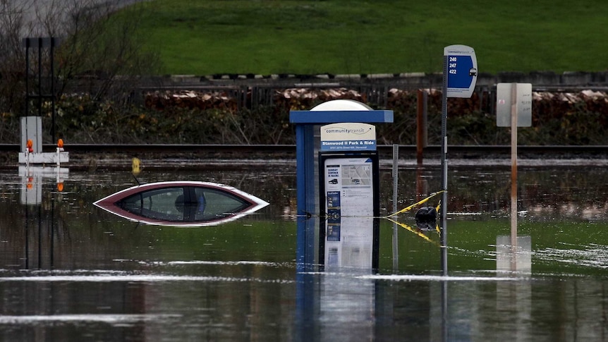 A bus stop and a car sit submerged in flood waters.