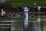A bus stop and a car sit submerged in flood waters.