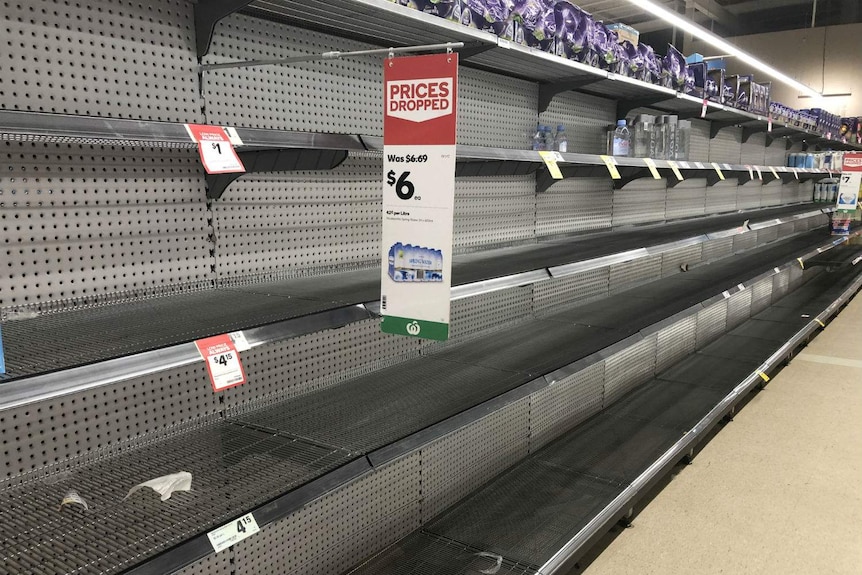 A row of empty supermarket shelves.