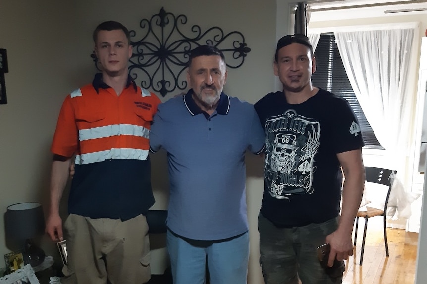 A family of three in a room with one in an orange shirt