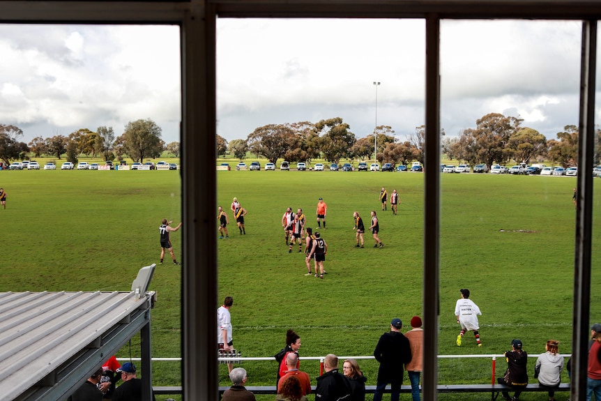 A window box overlooking a football ground with players running around