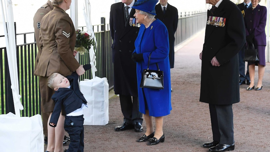 Michelle Lun holds on to her son Alfie, 2, as they greet the queen