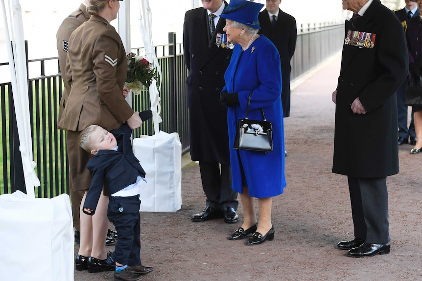 Michelle Lun holds on to her son Alfie, 2, as they greet the queen