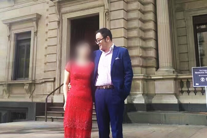 Nick Hao stands in front of the old treasury building in Melbourne with his wife.