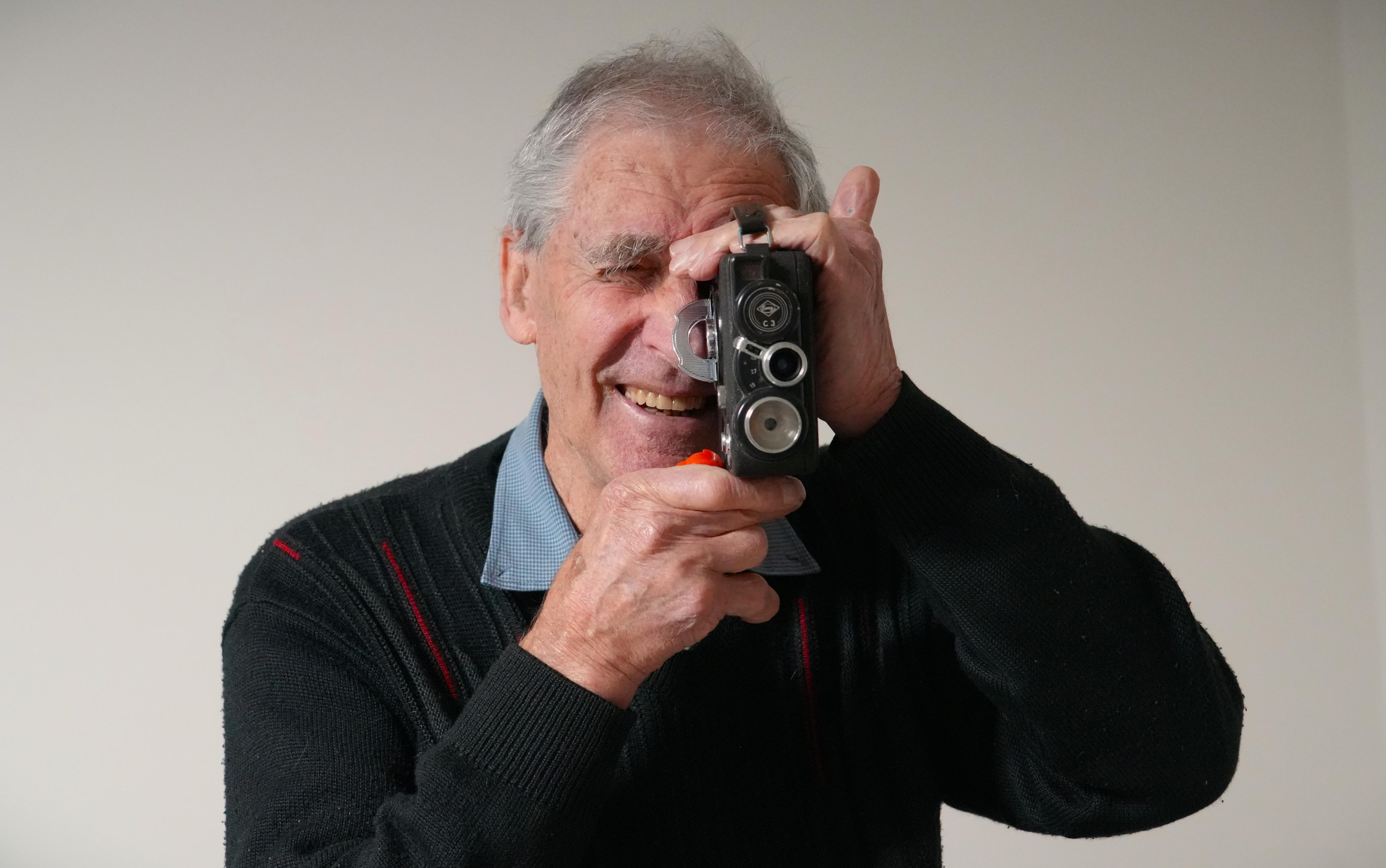 man holds old camera and smiles