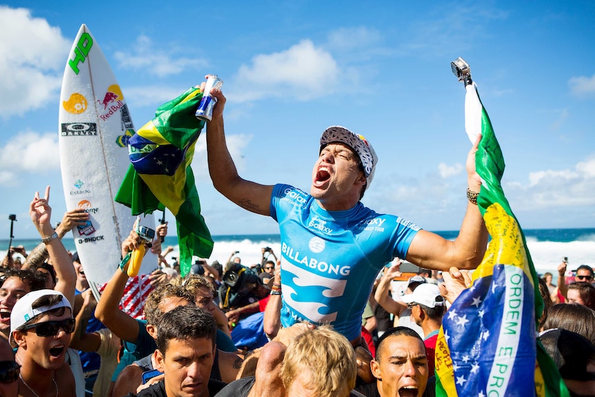 Adriano de Souza is carried from the surf on shoulders of supporters after winning the world surfing title.