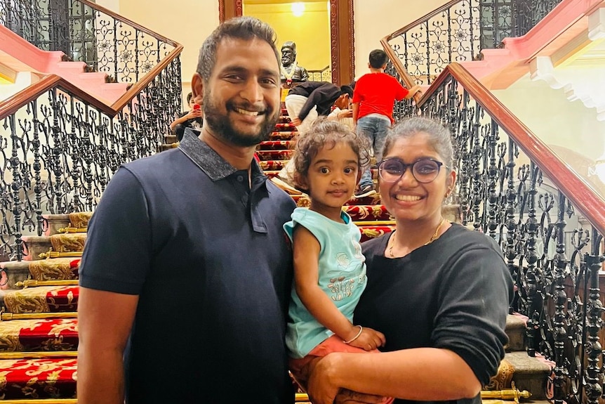 A man, woman and child stand on red carpeted steps in a hotel lobby.