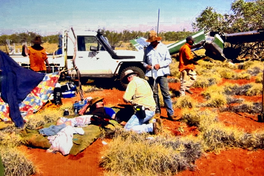 A doctor assists a patient in the middle of the red-dirt outback