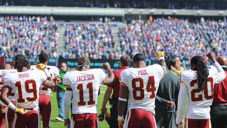 Washington Redskins players raise their fists during national anthem in NFL game against New York.