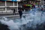 A man jumps over a canister of tear gas in Istanbul during a clash with police.