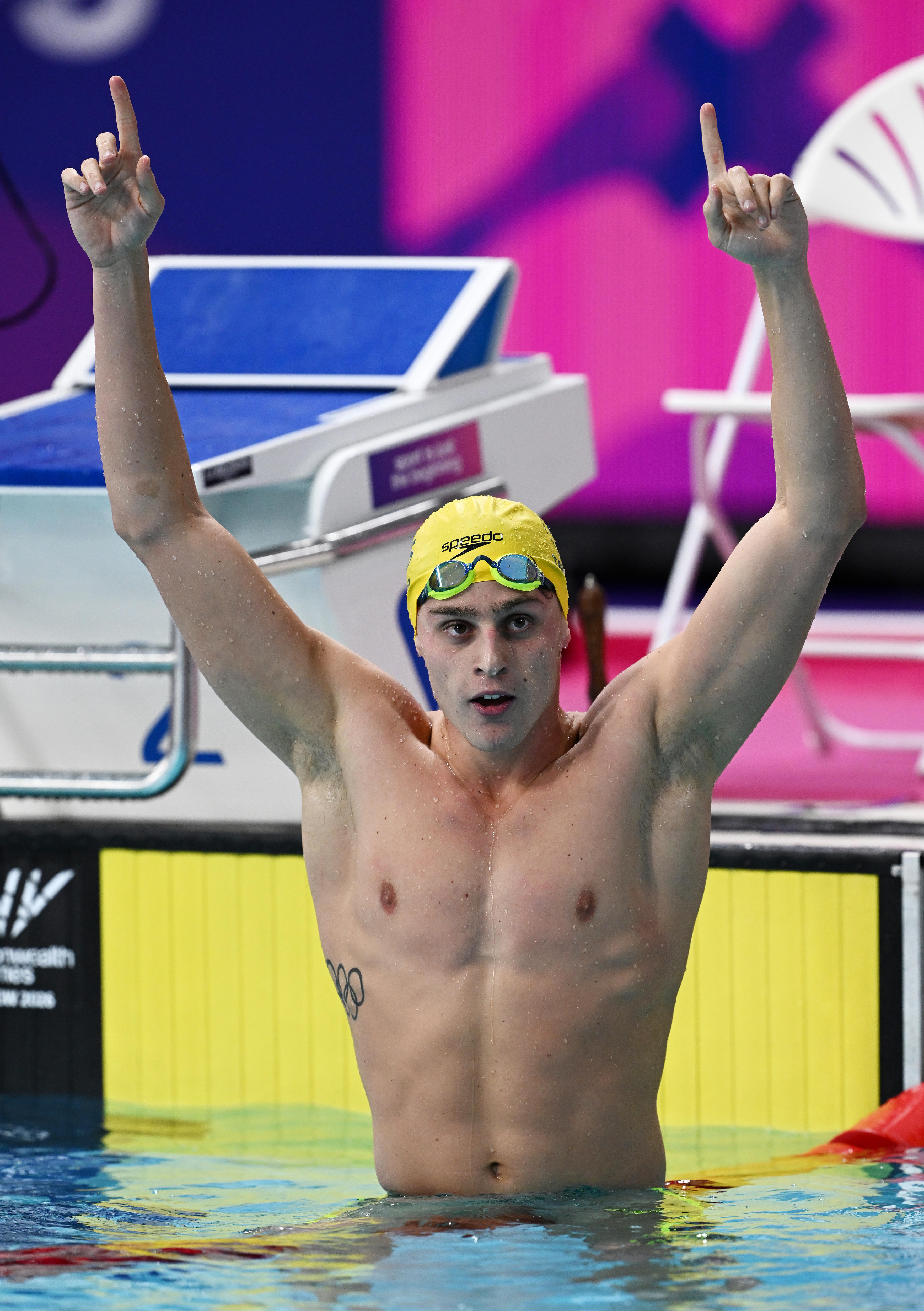 Swimmer Kai Taylor raises both hands as he sits in the pool after winning at the Commonwealth Games.