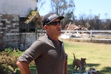 Ron standing on his property with his dogs in the background.