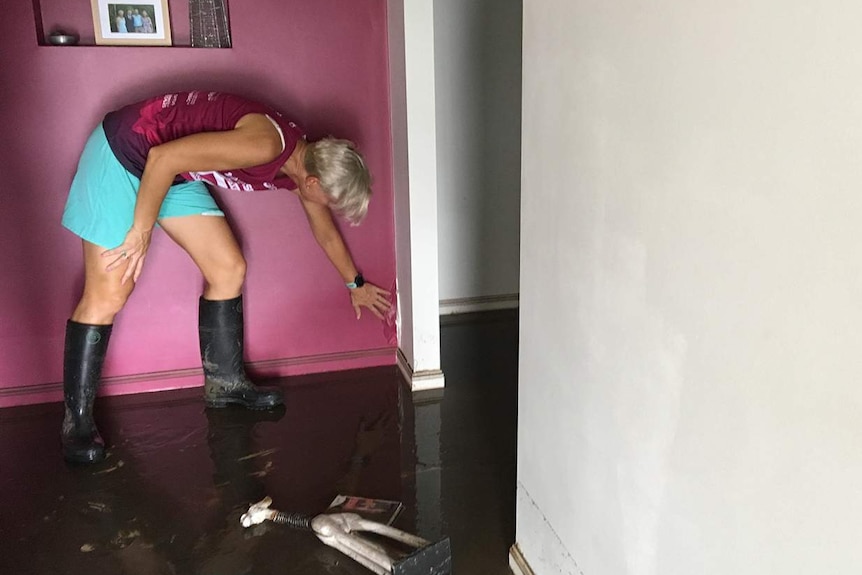 Carmel Linning looks at damage inside her flood-ravaged house.