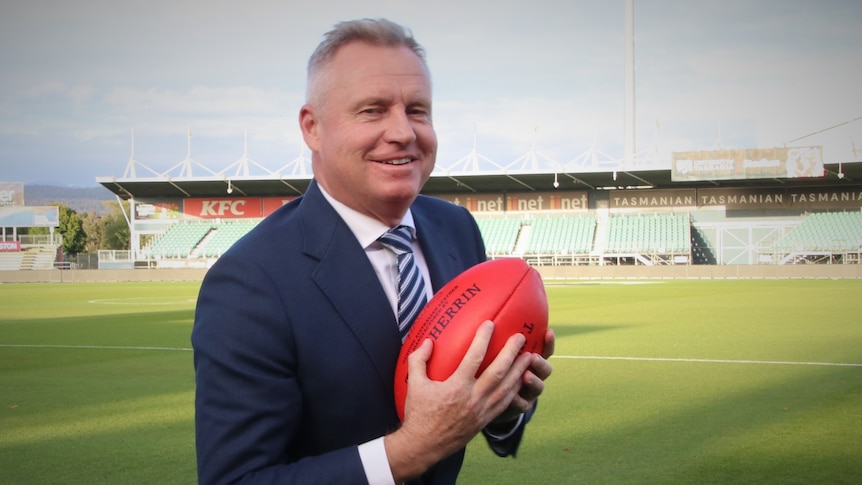 Jeremy Rockliff clutching an AFL football.