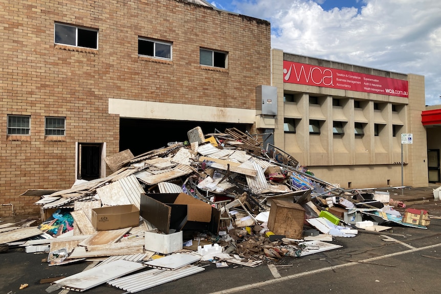 Large pile of rubbish in front of a two storey brick building