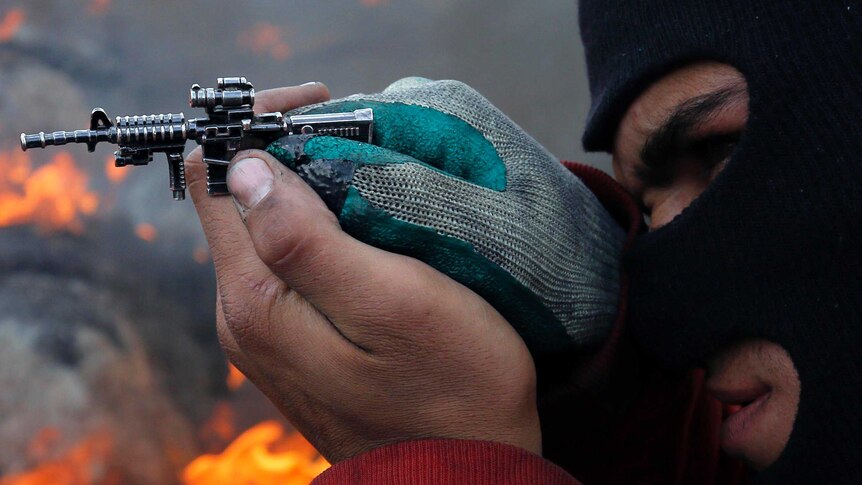 A Palestinian protester aims with a miniature toy gun during clashes with Israeli security forces.