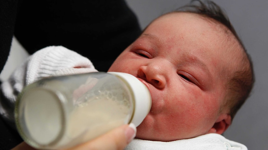 A baby drinks some milk from a bottle