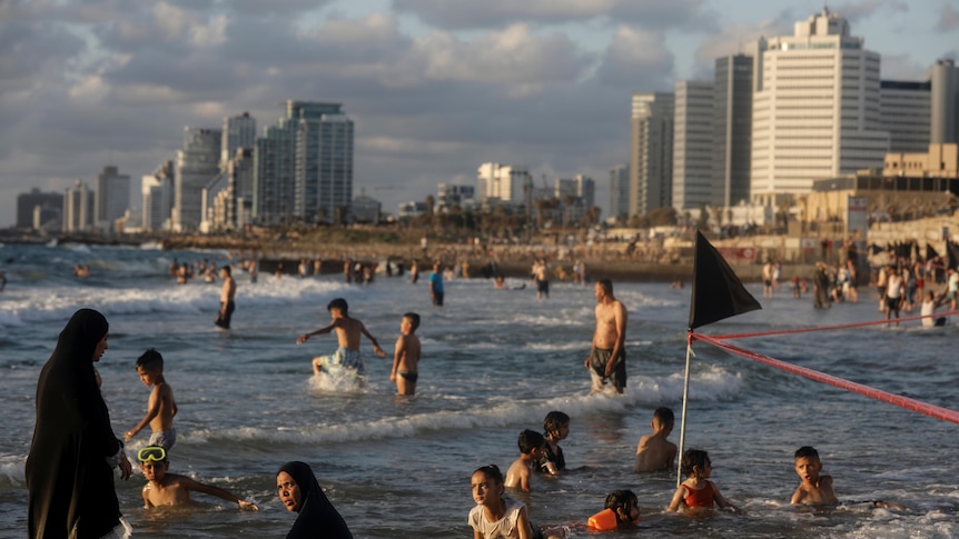 People playing in the beach with the cityscape of Tel Aviv in the background. 