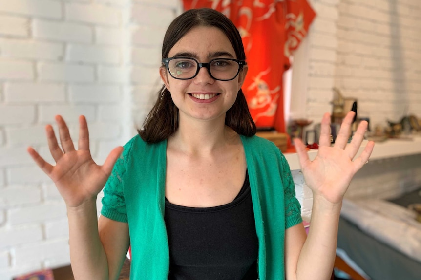 Young woman with hands in the air and palms facing forward, making AUSLAN sign for applause