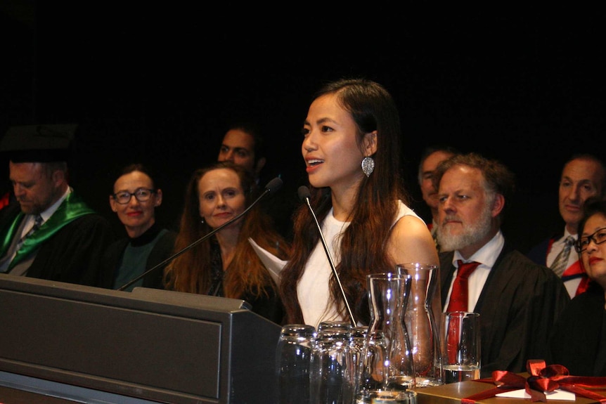 Sophy Ron delivers a speech on stage, as dignitaries watch on