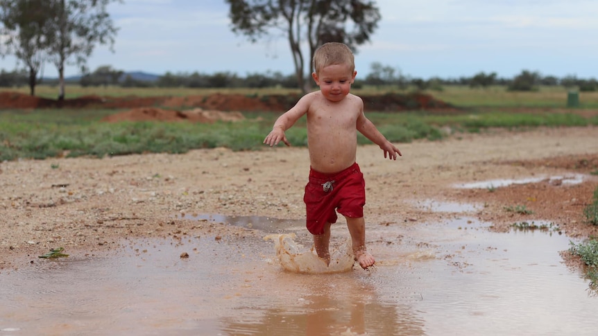 A boy running through puddles.