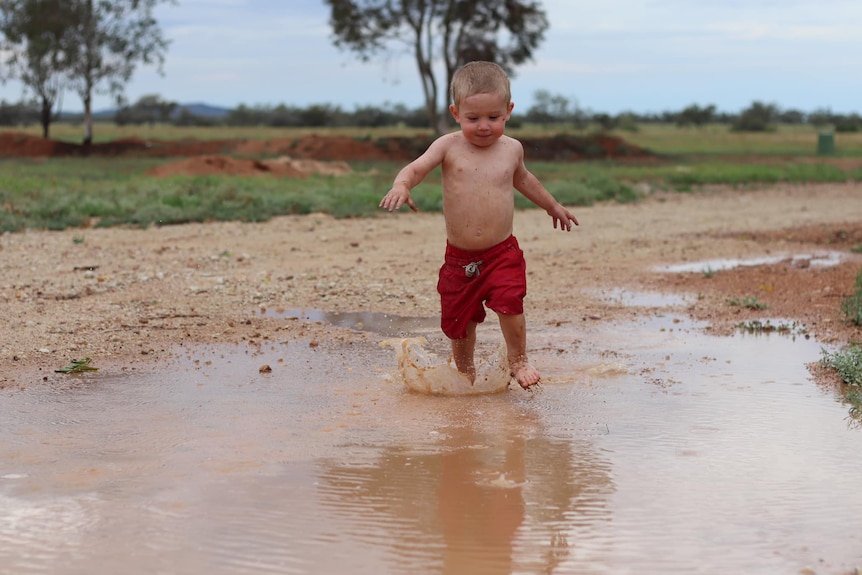 A boy running through puddles.